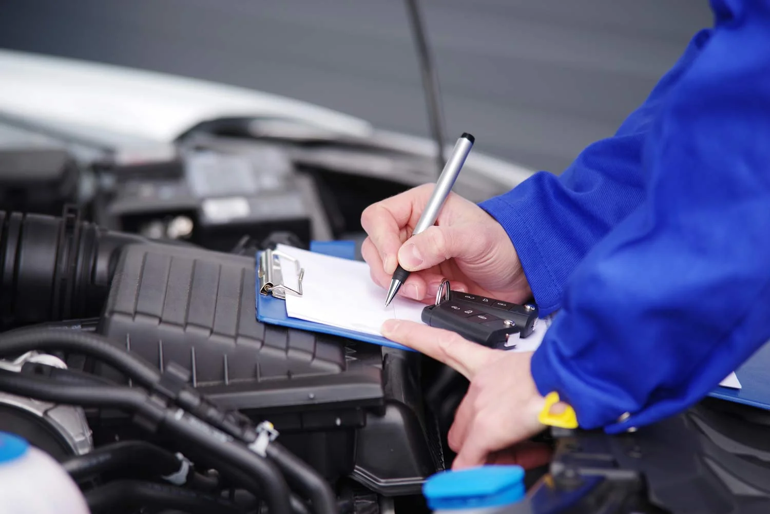 Mot technician writing a report after testing a car for mot